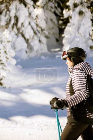Téléchargez les photos : Une seule jeune femme profite d'une journée ensoleillée de ski d'hiver, vêtue d'un équipement complet de neige avec des bottes de ski et des lunettes de soleil - en image libre de droit