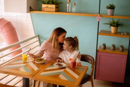 Foto de Madre e hija pasando un buen rato durante el desayuno con zumos recién exprimidos en la cafetería - Imagen libre de derechos