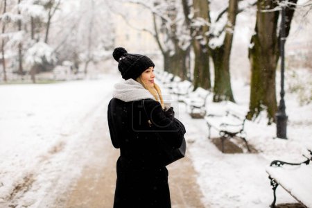 Photo for Pretty young woman in warm clothes enjoying in snow with takeaway coffee cup - Royalty Free Image