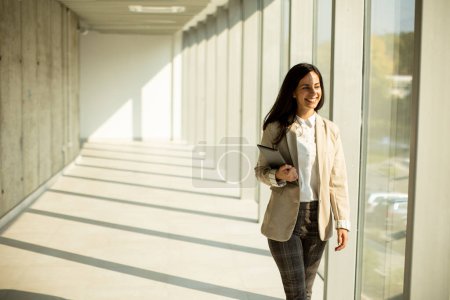 Photo for Young businesswoman walking on modern office hallway on a sunny day - Royalty Free Image