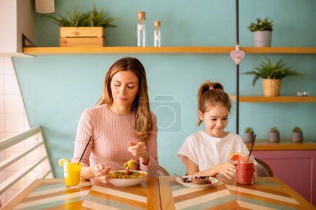 Foto de Madre e hija pasando un buen rato durante el desayuno con zumos recién exprimidos en la cafetería - Imagen libre de derechos