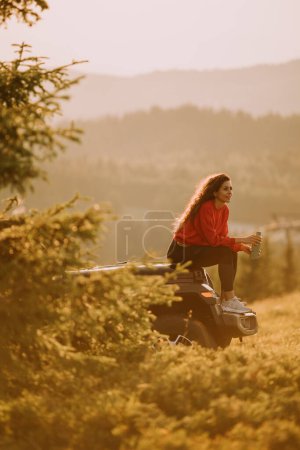 Photo for Pretty young woman relaxing on a terrain vehicle hood at countryside - Royalty Free Image