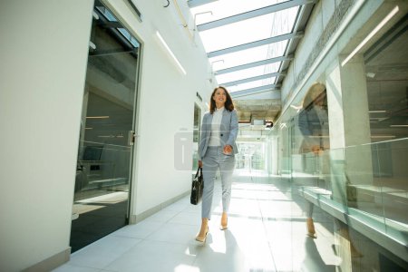 Foto de Mujer de negocios bastante joven caminando con maletín en el pasillo de la oficina - Imagen libre de derechos
