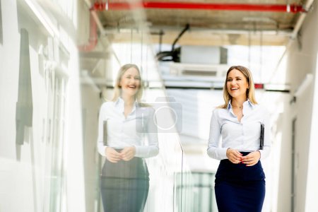 Photo for Pretty young woman walking with digital tablet in the office hallway - Royalty Free Image