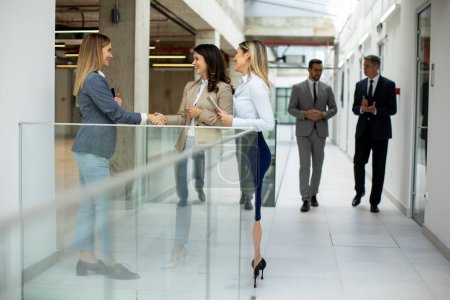 Photo for Three cute young business women having a discussion in the office hallway - Royalty Free Image