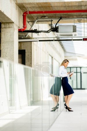 Photo for Pretty young woman working on digital tablet in the office hallway - Royalty Free Image