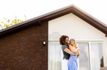 Téléchargez les photos : Beau jeune couple relaxant au bord de la piscine dans la maison arrière-cour - en image libre de droit