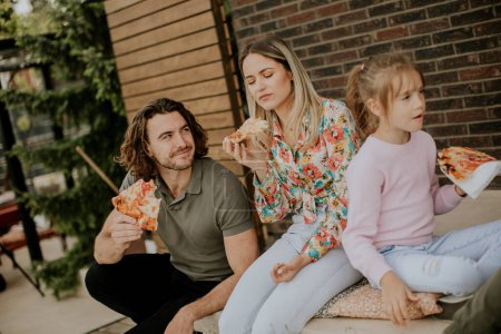 Photo for Happy young family eating pizza in the house backyard - Royalty Free Image
