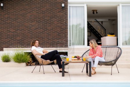 Photo for Handsome young couple relaxing by the swimming pool in the house backyard - Royalty Free Image