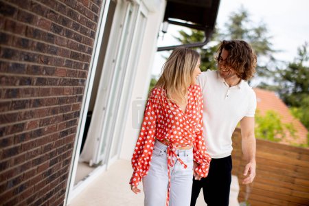 Photo for Handsome ymiling young couple in love walking in front of house brick wall - Royalty Free Image