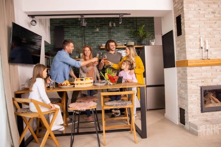 Téléchargez les photos : Deux familles heureuses trinquent au cidre tout en préparant le dîner dans la cuisine - en image libre de droit