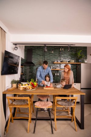 Foto de Familia joven feliz preparando verduras en la cocina - Imagen libre de derechos