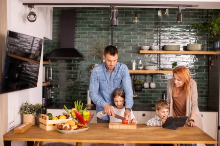 Photo for Happy young family preparing vegetables in the kitchen - Royalty Free Image