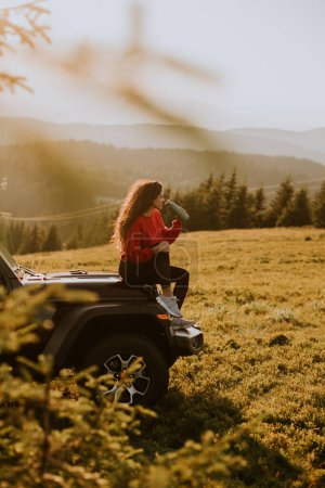 Téléchargez les photos : Pretty young woman relaxing on a terrain vehicle hood at countryside - en image libre de droit