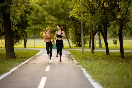 Téléchargez les photos : Deux jolies jeunes femmes qui courent sur une voie dans le parc - en image libre de droit