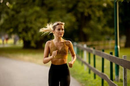 Photo for Pretty young woman running on a lane in the park - Royalty Free Image