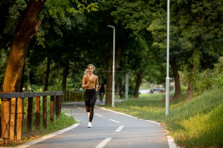 Photo for Pretty young woman running on a lane in the park - Royalty Free Image