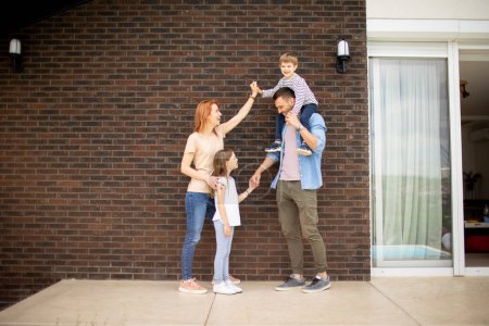 Téléchargez les photos : Famille avec une mère, père, fils et fille debout près du mur d'une maison en brique - en image libre de droit