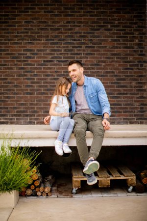 Photo for Father and his cute daughter have a good time in front of the house door - Royalty Free Image