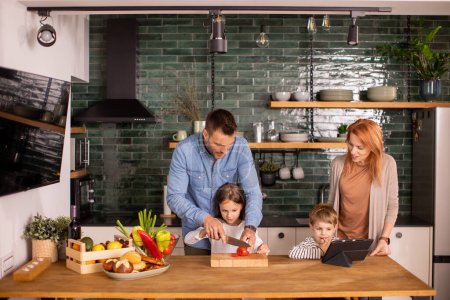 Photo for Happy young family preparing vegetables in the kitchen - Royalty Free Image