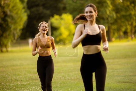 Téléchargez les photos : Deux jolies jeunes femmes qui courent dans le parc - en image libre de droit