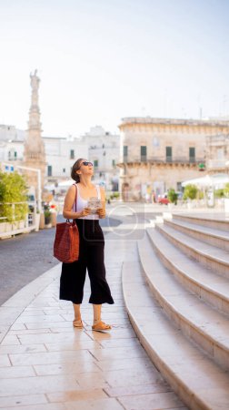 Téléchargez les photos : Touriste féminine avec une carte de la ville par la statue de Saint Oronzo à Ostuni, Italie - en image libre de droit