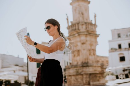 Photo for Female tourist with a city map by the Saint Oronzo statue in Ostuni, Italy - Royalty Free Image