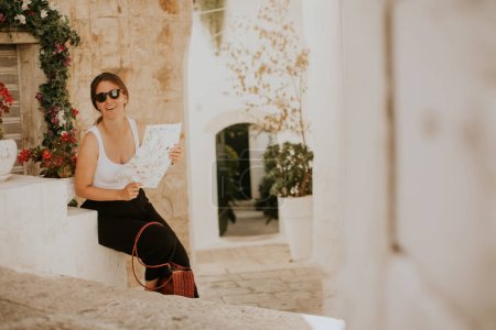 Foto de Turista femenina con un mapa de la ciudad en papel en las calles estrechas de Ostuni, Italia - Imagen libre de derechos