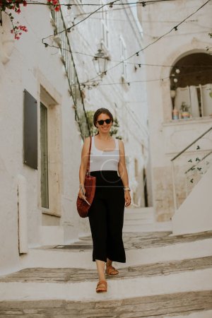 Téléchargez les photos : Touriste féminine avec une carte de ville en papier sur les rues étroites de Ostuni, Italie - en image libre de droit