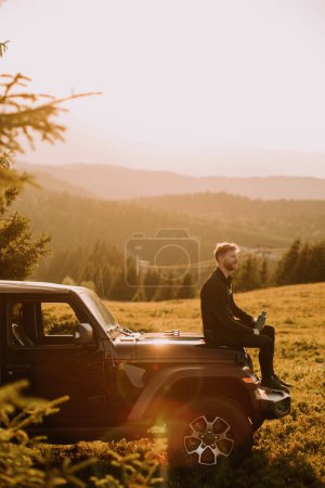 Photo for Handsome young man relaxing on a terrain vehicle hood at countryside - Royalty Free Image