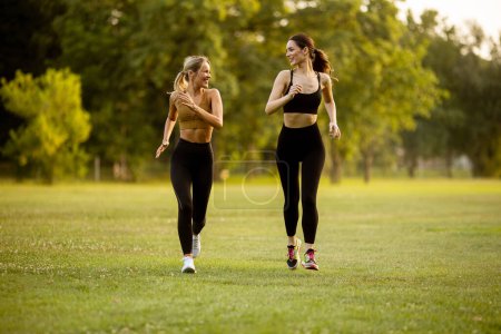 Téléchargez les photos : Deux jolies jeunes femmes qui courent dans le parc - en image libre de droit