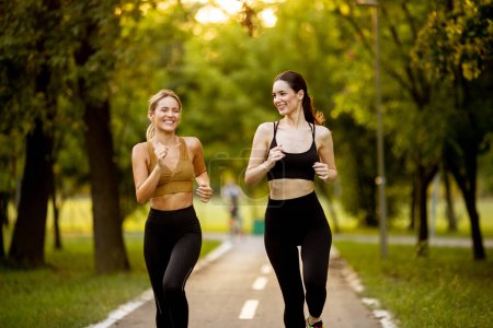 Téléchargez les photos : Deux jolies jeunes femmes qui courent sur une voie dans le parc - en image libre de droit