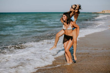 Téléchargez les photos : Deux jolies jeunes femmes s'amusent au bord de la mer lors d'une chaude journée d'été - en image libre de droit