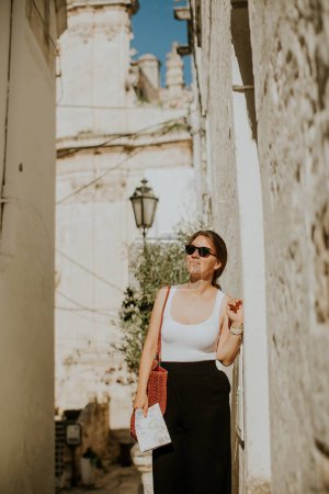 Photo for Female tourist with a paper city map on narrow streets of Ostuni, Italy - Royalty Free Image