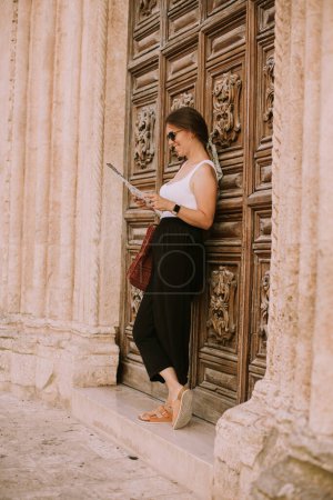 Téléchargez les photos : Touriste féminine avec une carte de la ville près de l'église San Francesco d'Assisi à Ostuni, Italie - en image libre de droit