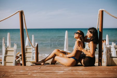 Photo for Two smiling young women in bikini sitting and enjoying vacation on the beach - Royalty Free Image