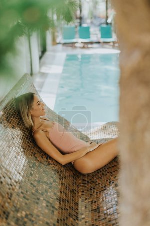 Foto de Mujer joven y bonita relajándose junto a la piscina cubierta - Imagen libre de derechos