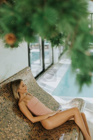 Téléchargez les photos : Jolie jeune femme relaxante au bord de la piscine intérieure - en image libre de droit