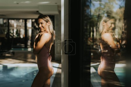 Photo for Pretty young woman standing by the indoor swimming pool - Royalty Free Image