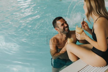 Photo for Handsome young couple relaxing by the indoor swimming pool - Royalty Free Image