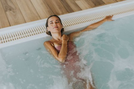 Téléchargez les photos : Jolie jeune femme relaxante dans la piscine intérieure - en image libre de droit
