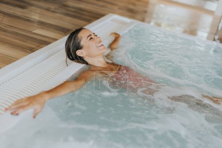 Téléchargez les photos : Jolie jeune femme relaxante dans la piscine intérieure - en image libre de droit