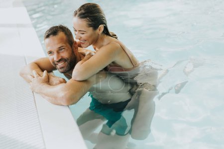 Téléchargez les photos : Beau jeune couple relaxant dans la piscine intérieure - en image libre de droit