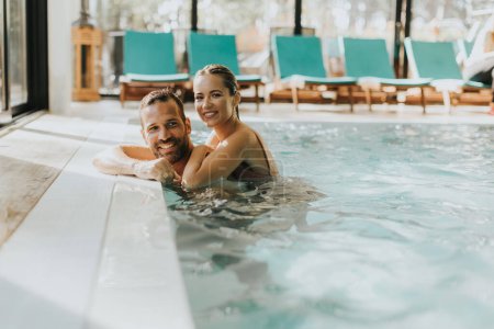 Foto de Hermosa pareja joven relajándose en la piscina cubierta - Imagen libre de derechos