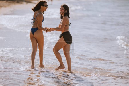 Foto de Dos guapas jóvenes divirtiéndose en la playa en el caluroso día de verano - Imagen libre de derechos
