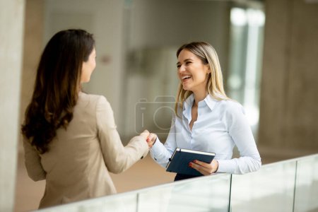 Photo for Two pretty young business women with paper notebook in the office hallway - Royalty Free Image