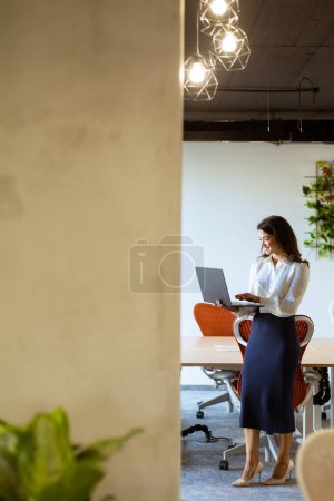Foto de Mujer de negocios bastante joven con portátil en el pasillo de la oficina - Imagen libre de derechos
