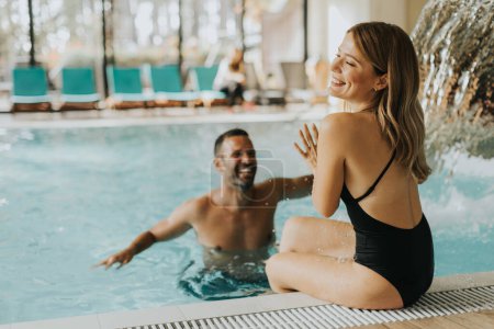 Téléchargez les photos : Beau jeune couple s'amusant dans la piscine intérieure - en image libre de droit