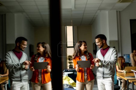 Téléchargez les photos : Jeune couple d'affaires debout avec tablette numérique devant son équipe au bureau moderne - en image libre de droit