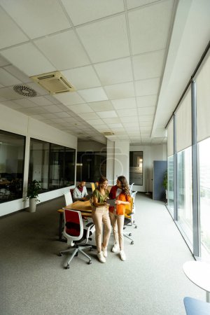 Foto de Dos mujeres de negocios bastante jóvenes con tableta digital en la oficina moderna - Imagen libre de derechos